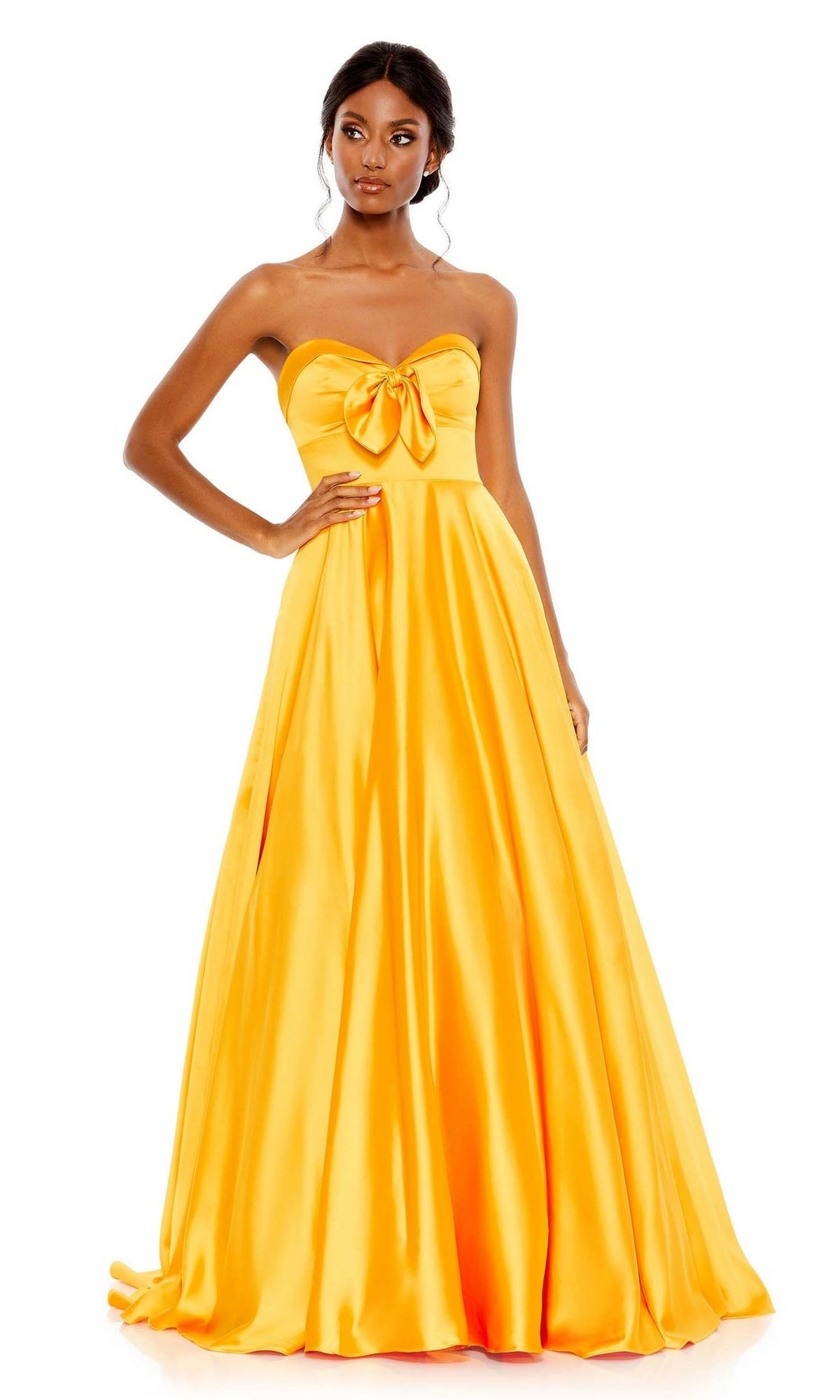 A woman stands against a white background wearing the Long Formal Dress 67995 by Mac Duggal, a strapless marigold yellow satin gown featuring a sweetheart A-line silhouette and front bow detail.